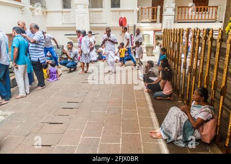 KANDY, SRI LANKA - JULY 19, 2016: White clothed Buddhist devotees pray in the Temple of Sacred Tooth Relic during Poya Full Moon holiday. Stock Photo