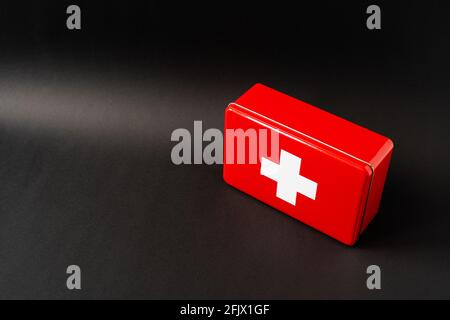 Red simplistic first aid box, black background with light gradient Stock Photo