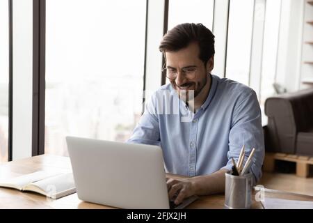 Smiling man work on laptop browsing internet Stock Photo