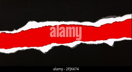 Hole ripped in paper on red background Stock Photo