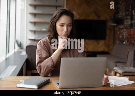 Pensive female worker busy browsing computer in office Stock Photo