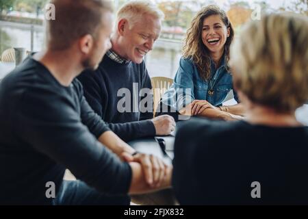 Group of business people discussing a contract and smiling together in office boardroom. Cheerful business team discussing over an agreement in meetin Stock Photo