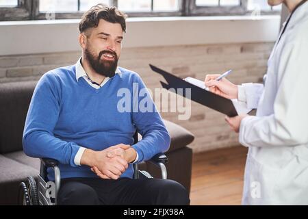 Handsome ex-serviceman in a wheelchair having a physician's visit Stock Photo