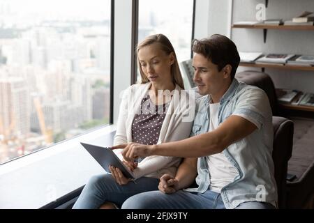 Diverse employees work on tablet discussing ideas Stock Photo