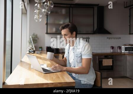 Caucasian man sit at home kitchen using laptop Stock Photo