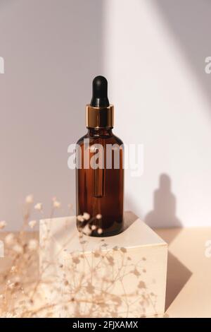 Natural essential oil or serum in brown glass bottle on a wooden podium. Alternative medicine, beauty skin care product. Copy space. Neutral Stock Photo