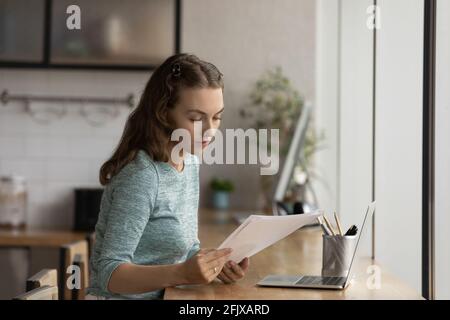 Young female employee work with documents using laptop Stock Photo