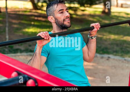 Fit man doing calisthenics workout crunches sit ups on parallel