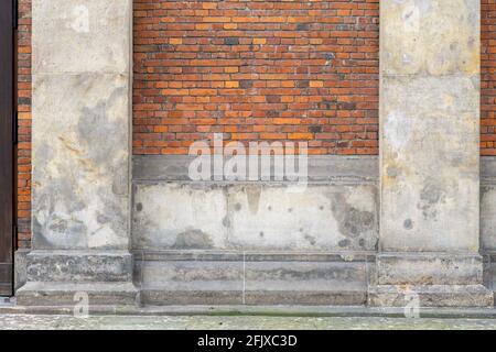 Old brick wall with aged whitewashed pillars on the side of a street Stock Photo