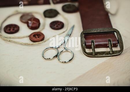 Buttons, scissors and leather belt on light wood Stock Photo
