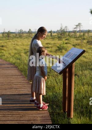 Children standing in Nature Reserve looking at Information Board Stock Photo