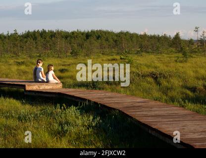 Children sitting on Boardwalk looking at Nature reserve Landscape Stock Photo