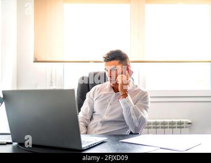 executive taking a call while working from his computer at home Stock Photo