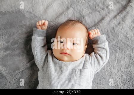 Cute two months newborn Asian Chinese baby boy lying on bed looking. Stock Photo