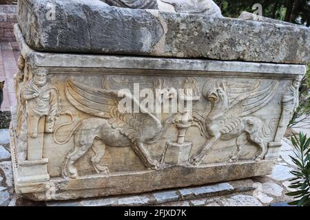 Ancient carved marble casket with two magnificent griffins carved on the side and repaired rock top sitting beside the road near the archeological rui Stock Photo