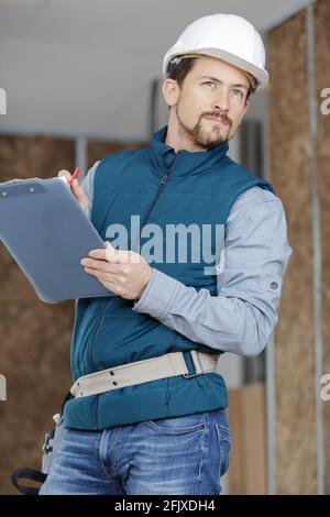 male builder in helmet with clipboard taking notes Stock Photo