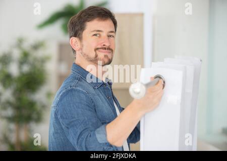 man fixing curtain on to rail Stock Photo