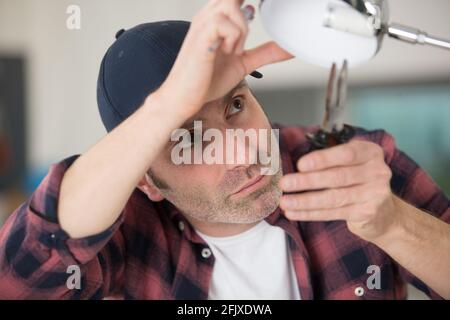 a man fixes the lamp with a screwdriver Stock Photo
