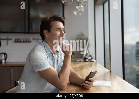 Pensive man use smartphone look in distance thinking Stock Photo