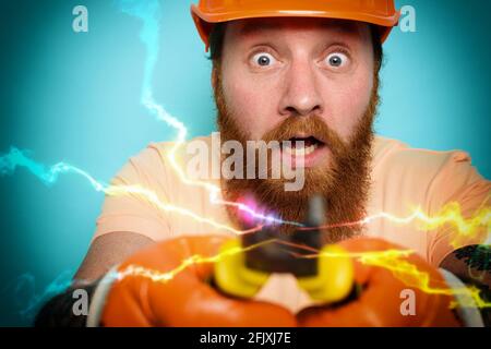 Incompetent worker electrician is unsure about his work. cyan background Stock Photo