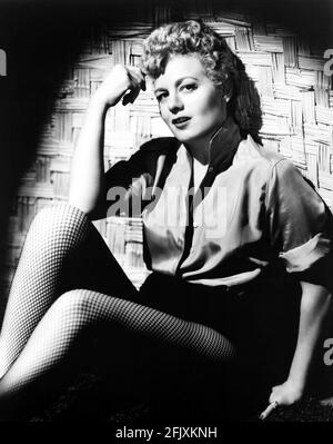 1951 c, USA . : The movie actress SHELLEY WINTERS ( born Shirley Schrift , Saint Louis , MT 1922 ) , wife of italian stage and movie actor VITTORIO GASSMAN , photo by Universal International Studios - CINEMA - FILM  - blondie - capelli biondi - bionda - blonde hair - leggy pose - gambe - legs - calze a rete - hot pants   ----  Archivio GBB Stock Photo