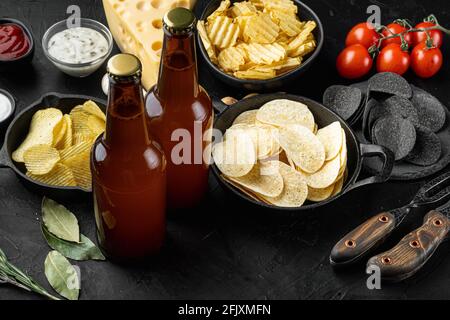 Potato chips. Beer snacks, sauce set, on black stone background Stock Photo