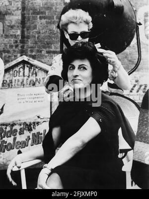 1959 : The italian movie actress ANNA  MAGNANI smiled for the camera on the set of  THE FUGITIVE KIND ( Pelle di serpente )  by Sidney Lumet , from a play by Tennessee Williams , United Artist Productions . Photo taken by actor Paul Newman . While her co-star JOANNE WOODWARD aid like hairdo repair the Magnani  after one of her tempestuos scenes. PAUL NEWMAN , husband of star JOANNE WOODWARD , visited the set and acted as part-time still photographer for the production.- CINEMA - FILM - attrice  - attore - parrucchiera - smile - sorriso - sul set  ----   Archivio GBB Stock Photo