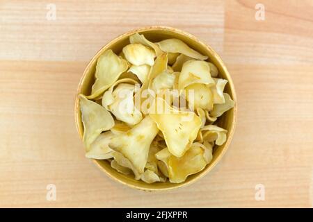 Thin slice dried Brown Lily Bulb, also called Bai He used in traditional Chinese medicine in wooden bowl, top view on wooden background Stock Photo