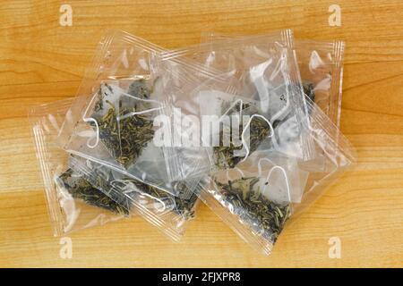 White tea leaves in transparent pyramid tea bag in clear package on wooden background Stock Photo