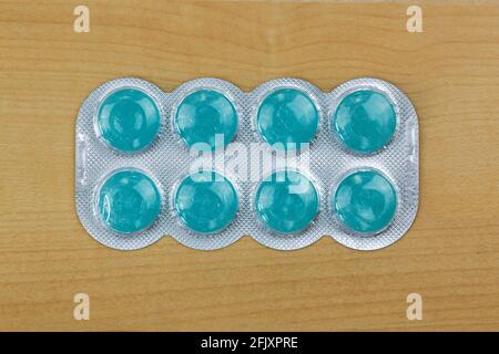Blue lozenges medicine for severe sore throats with 2 antiseptic agents, anesthetic for effective pain relief, Top view on wooden background Stock Photo