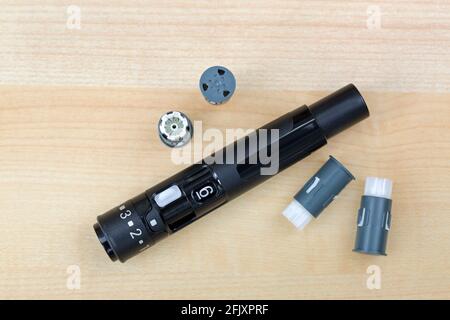 Finger pricker, lancing device kit with drum and preloaded lancets for convenience to check blood Glucose on wooden background Stock Photo