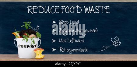 Reduce food waste text, ways to reduced food waste listed on chalk board with compost bin, sustainable living and zero waste Stock Photo