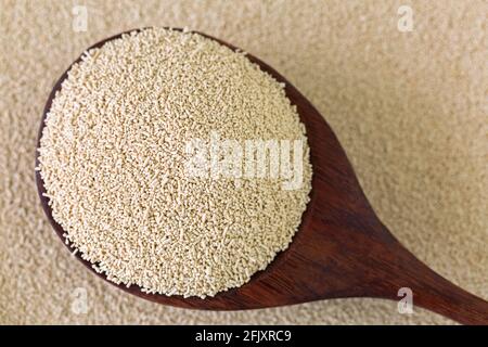 Active dry Baking yeast granules in wooden spoon, top view Stock Photo