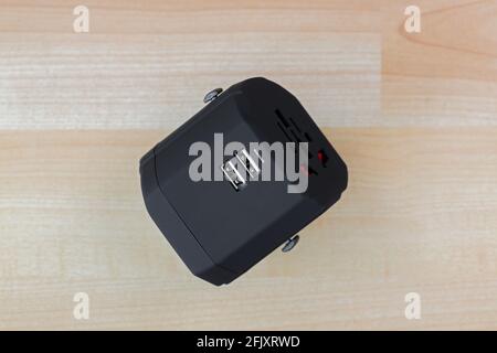 Universal Power Adapter, plug for travel with dual USB ports. All in one travel adaptor in black on wooden background Stock Photo