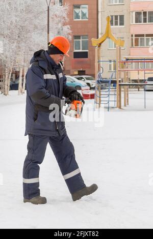 Worker with a chainsaw in hand at the assembly site Stock Photo
