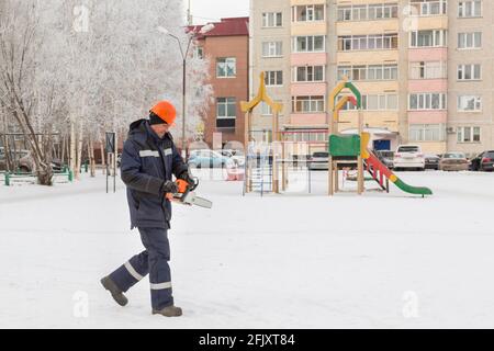 Worker with a chainsaw in hand at the assembly site Stock Photo