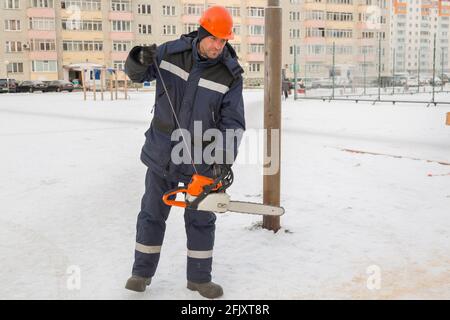Worker with a chainsaw in hand at the assembly site Stock Photo