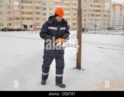 Worker with a chainsaw in hand at the assembly site Stock Photo