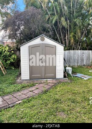Old backyard tool shed with shovel on the outside of a yard. Many trees are surrounding the shed. Stock Photo