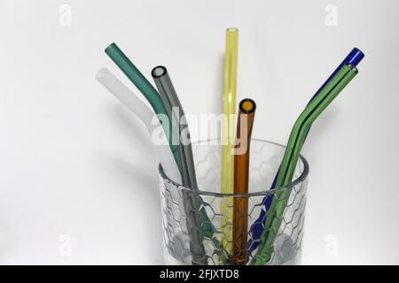 Colorful reusable glass straws in a clear glass cup. An alternative replacement for classic disposable plastic drinking straw great for the environment Stock Photo