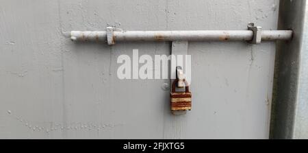 The lock on a chain hangs on a gate with white plate Stock Photo