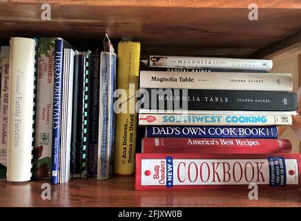 Kitchen Cookbooks bunched together on shelf. Many different cuisines are shown. Stock Photo