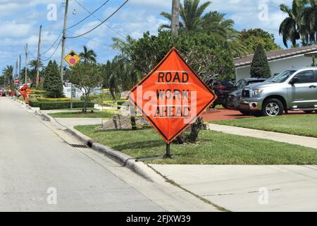 Road work ahead sign in a street in they city of Hialeah. The construction site is approaching in a residential area. Stock Photo