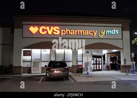 Night time shot of the entrance of a CVS that also has Spanish incorporated into its signage. CVS y mas. Location where COVID-19 vaccines are given Stock Photo