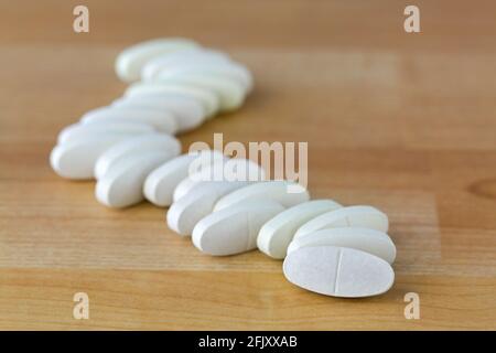 Oval Calcium Magnesium vitamin tablets to prevent osteoporosis, bone health formula on wooden background Stock Photo