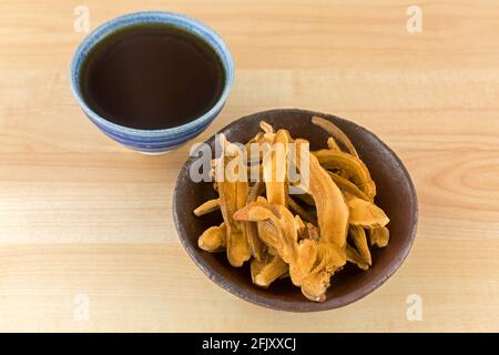 Bowl of herbal sliced dried Lingzhi mushroom next to hot Reishi tea. It is medicinal mushroom in traditional Chinese medicine Stock Photo
