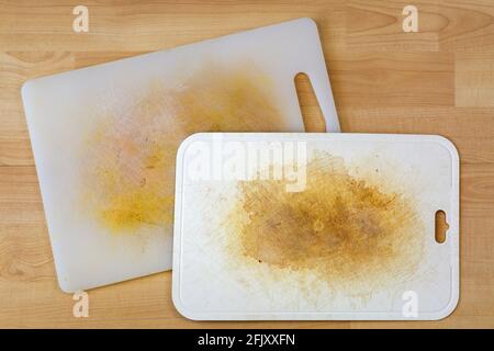 Dirty white plastic cutting board with dark stains, scratch, on wooden background Stock Photo