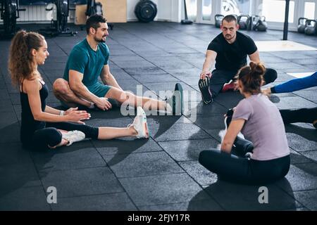 Fitness coach and his clients performing the seated forward bend Stock Photo