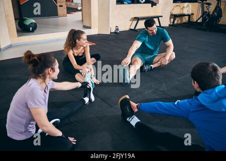Flexible women and men performing the seated forward bend Stock Photo