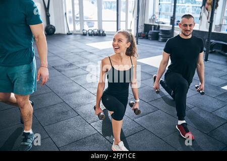 Smiling athletes doing the low lunge with dumbbells Stock Photo